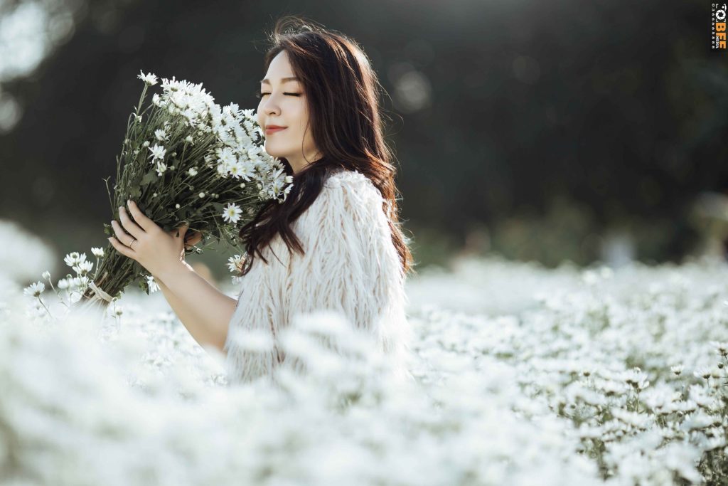 Nữ sinh mặc áo dài trắng ôm bó hoa cúc họa mi khi chụp ảnh kỷ yếu
