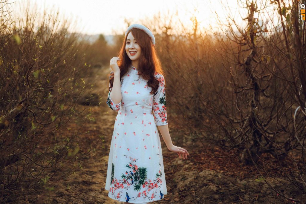 Áo dài trắng họa tiết hoa kết hợp mũ nồi, chụp ngoại cảnh lúc hoàng hôn