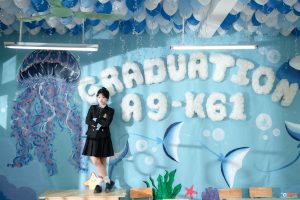 Nữ sinh đứng trước tường kỷ yếu Graduation A9-K61 vẽ sứa tím và cá voi