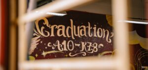 Tường kỷ yếu Graduation A10-K58 viết chữ vàng kiểu calligraphy trên nền nâu