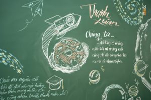 Vẽ bảng kỷ yếu bằng phấn trắng: hoa hồng lớn và lời nhắn viết tay trên bảng xanh