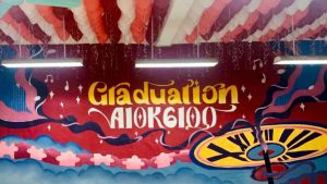Trang trí lớp kỷ yếu với khuông nhạc và chữ vàng Graduation trên nền đỏ