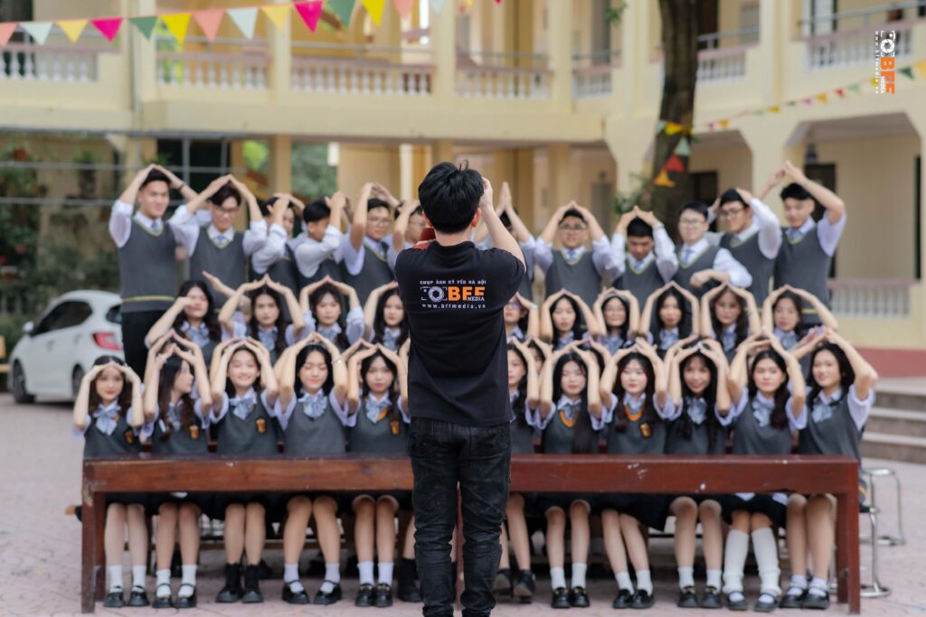 Thợ chụp hướng dẫn cả lớp tạo dáng ảnh tập thể kỷ yếu ở sân trường