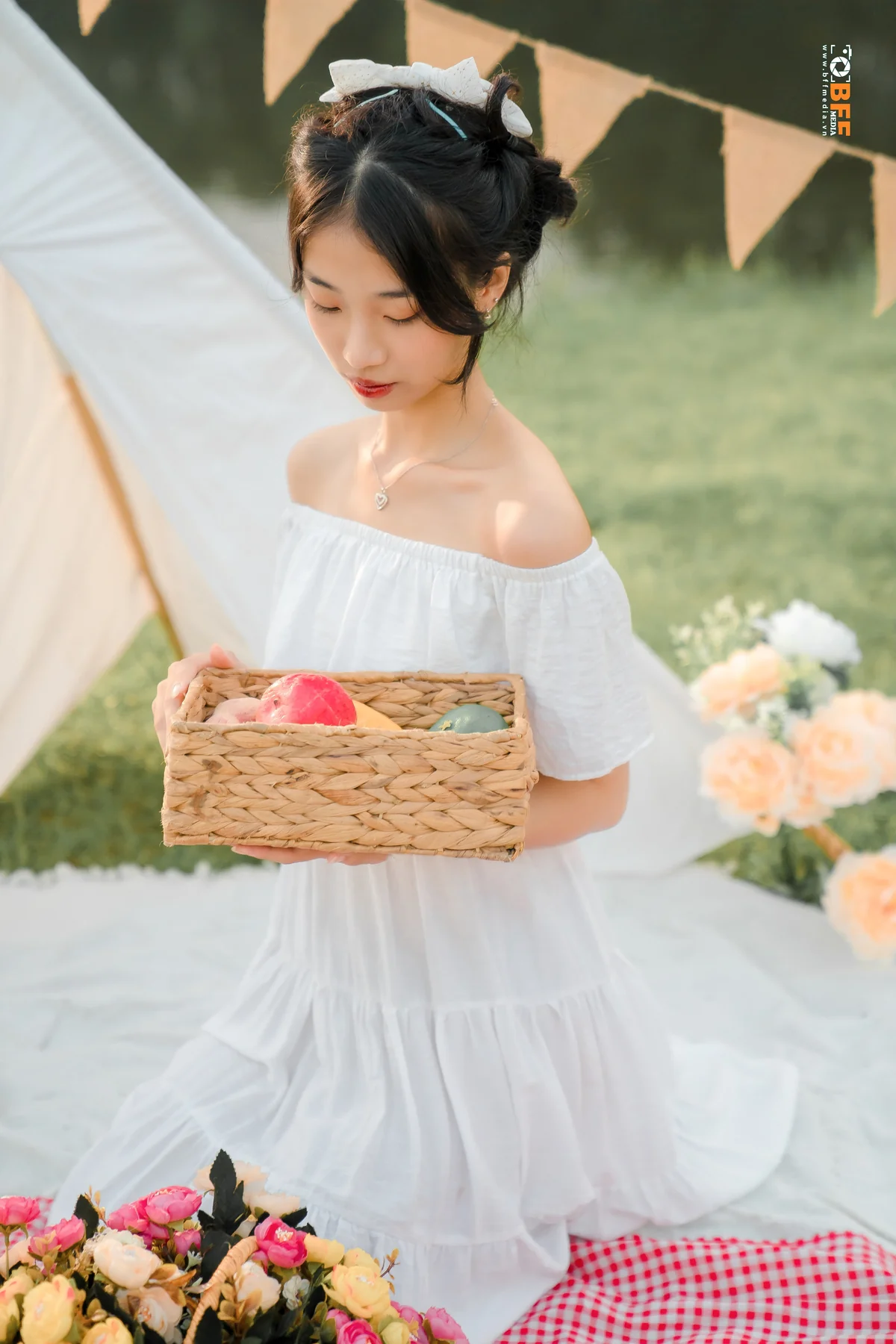 Nữ sinh váy trắng cầm giỏ hoa tạo dáng chụp kỷ yếu ngoài trời