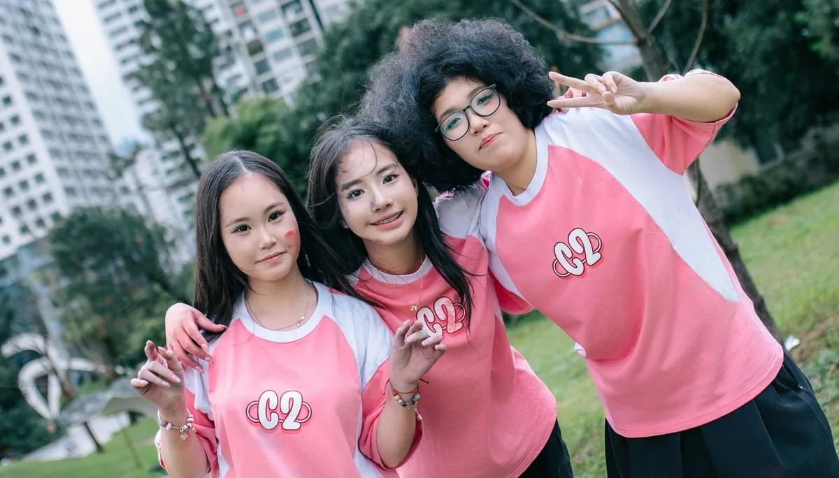Ba bạn nữ mặc áo lớp màu hồng khoác vai nhau trong ảnh kỷ yếu
