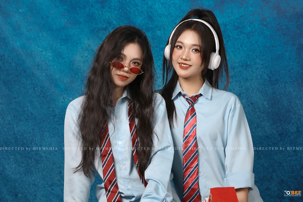 Hai bạn thân đeo cà vạt đỏ chụp ảnh kỷ yếu đôi trên nền xanh studio