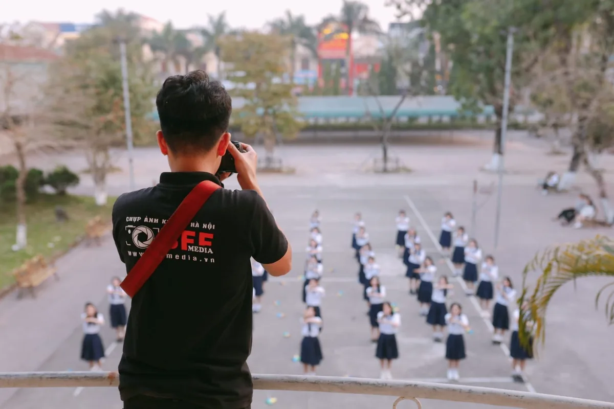 Thợ BFFMEDIA đứng trên ban công chụp xuống đội hình học sinh xếp trên sân trường