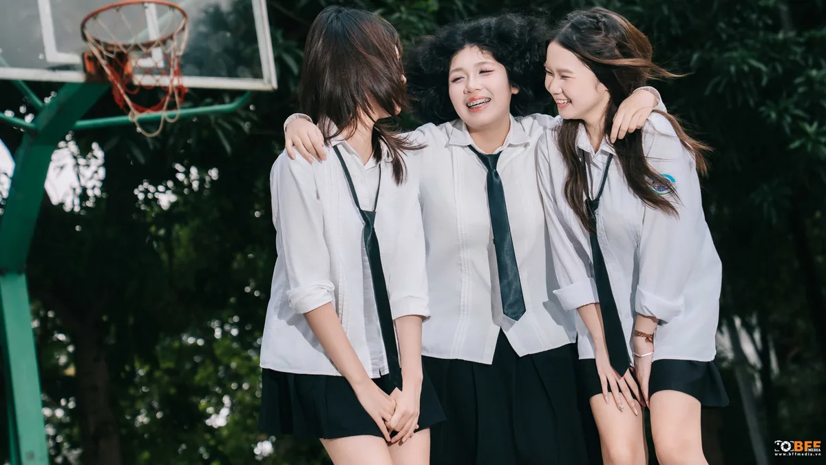 Ba bạn nữ khoác vai nhau cười tươi dưới bảng bóng rổ trong ngày chụp kỷ yếu